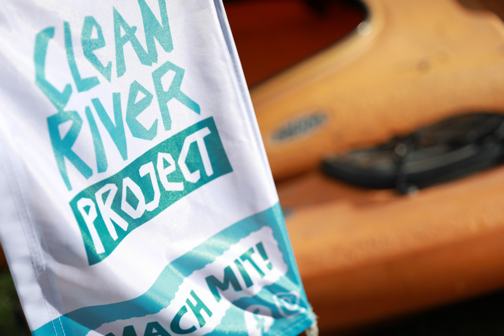 Eine Fahne mit der Aufschrift Clean River Project, im Hintergrund Kajaks.