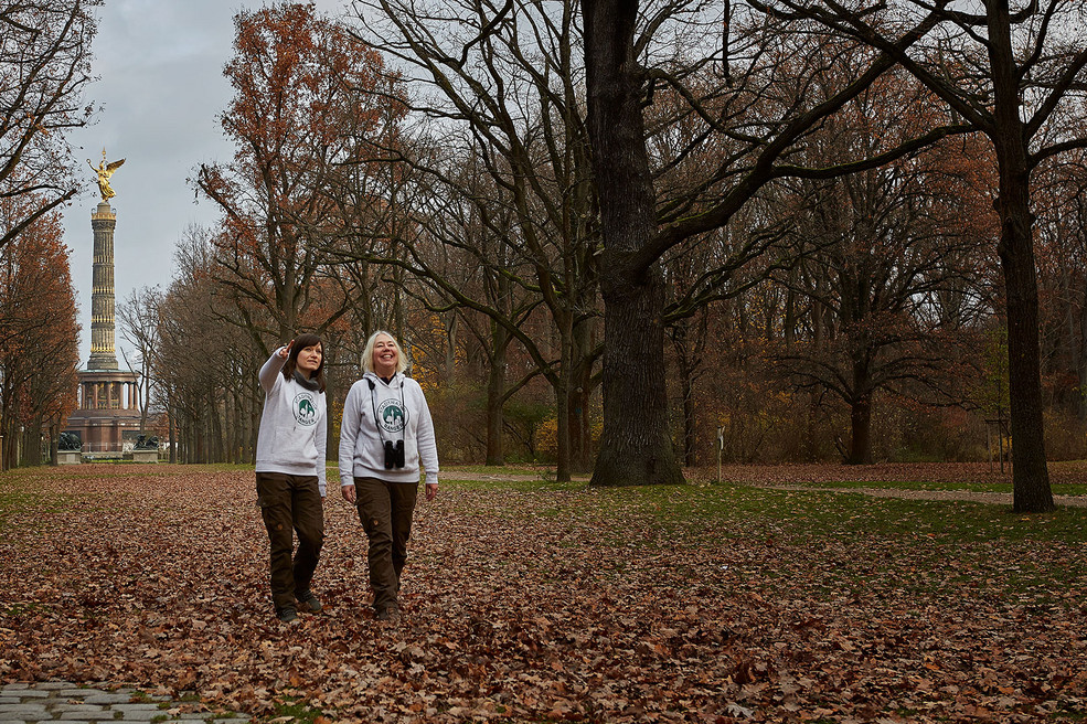 Zwei Rangerinnen zu Fuß unterwegs im Tiergarten mit der Siegessäule im Hintergrund 