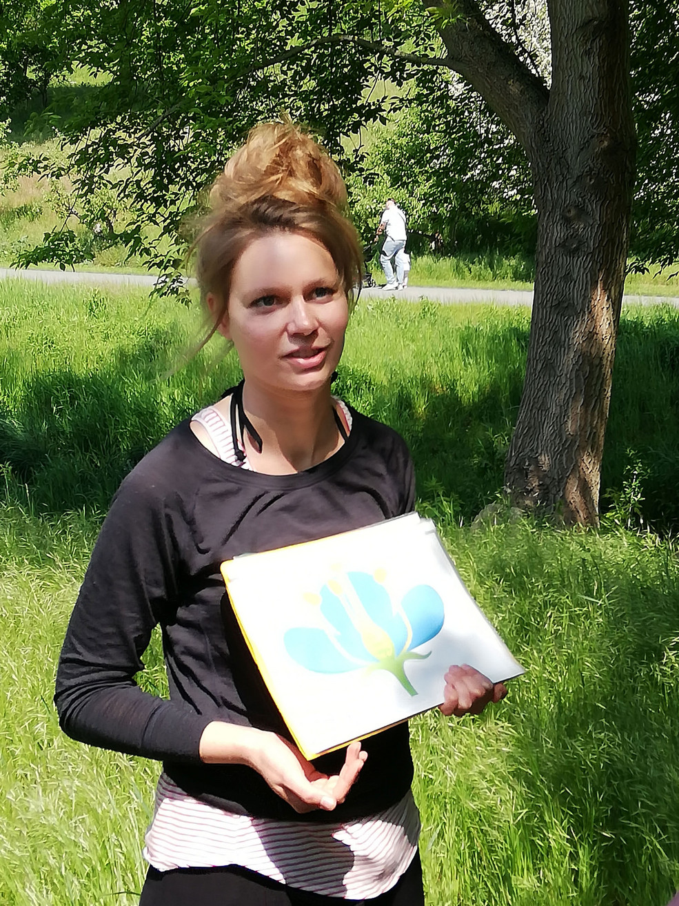 Zu sehen ist eine Frau, die eine Abbildung einer Insektenart in ihrer Hand hält