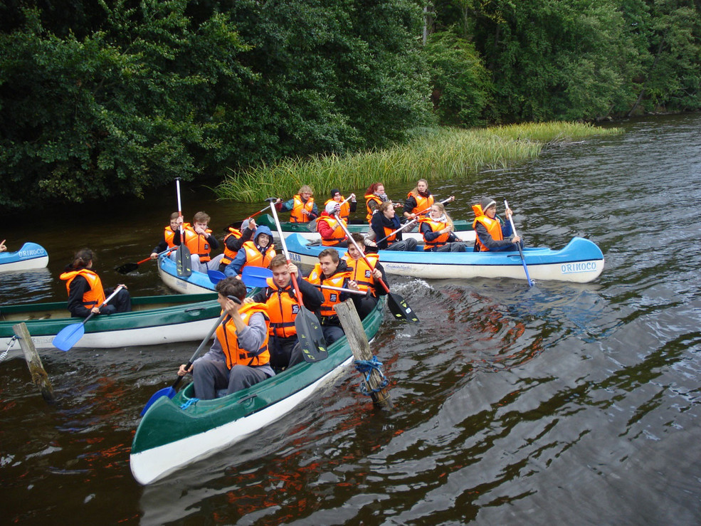 Eine Gruppe von jungen Menschen, die auf kleinen Booten paddeln.